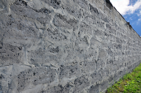 Weathered stained old grey block wall background. Texture of an old colored wall of several floors with lots of rows of blocksの写真素材