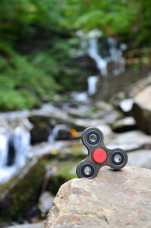 The wooden spinner lies on the rocks against the background of a small waterfall and a riverの写真素材