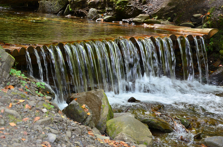 Handmade wooden water drains from small treated beams. A beautiful fragment of a small waterfallの写真素材