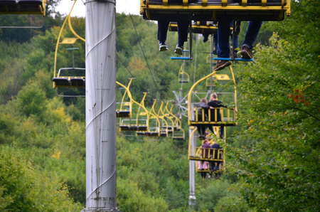 People ride on a cable car. The legs of passengers hang over the mountain forestの写真素材
