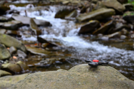 The wooden spinner lies on the rocks against the background of a small waterfall and a riverの写真素材
