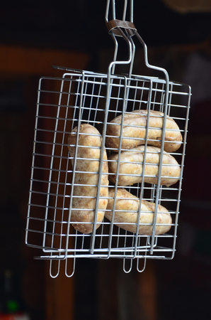 A small hand grill is filled with fried thick sausages on a dark backgroundの写真素材