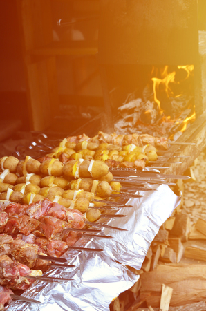 Raw meat and potatoes are planted on metal skewers. The process of cooking shish kebabs. Russian and Ukrainian camp foodの写真素材