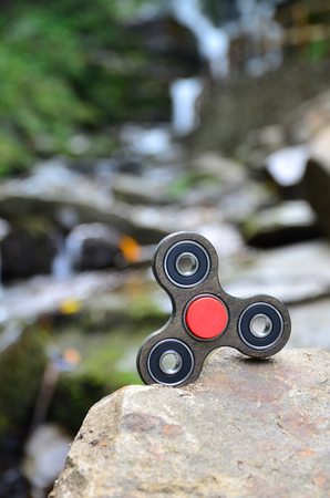 The wooden spinner lies on the rocks against the background of a small waterfall and a riverの写真素材