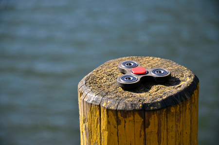 A wooden spinner lies on a wooden bar against a background of river waterの写真素材