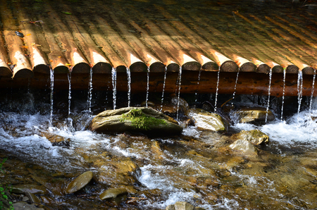 Handmade wooden water drains from small treated beams. A beautiful fragment of a small waterfallの写真素材