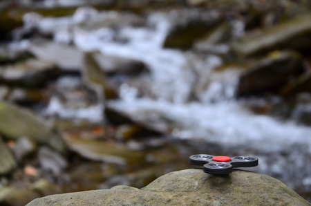 The wooden spinner lies on the rocks against the background of a small waterfall and a riverの写真素材