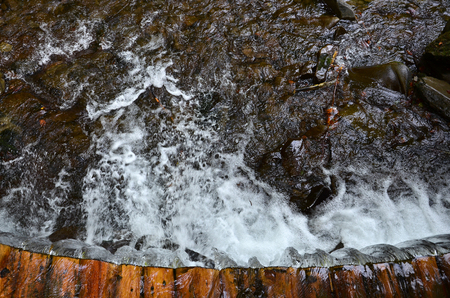 Handmade wooden water drains from small treated beams. A beautiful fragment of a small waterfallの写真素材