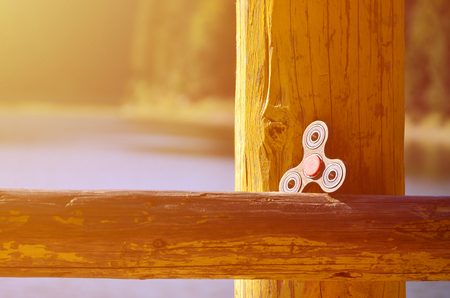 A wooden spinner lies on a wooden bar against a background of river waterの写真素材