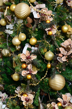 Decorating Christmas tree close up. Decoration bulb, green fir tree, golden x-mas toys and lights. Use for Christmas and New years celebration backgroundの写真素材