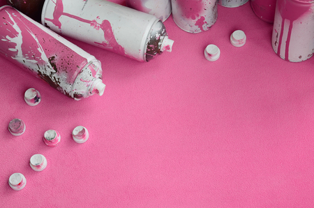 Some used pink aerosol spray cans and nozzles with paint drips lies on a blanket of soft and furry light pink fleece fabric. Classic female design color. Graffiti hooliganism conceptの写真素材