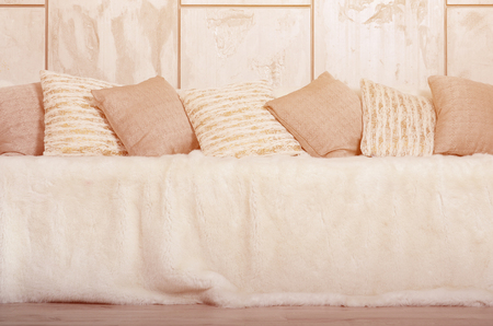 Many pillows lie on the couch, which is covered with a large plush veil against the background of a marble wallの写真素材