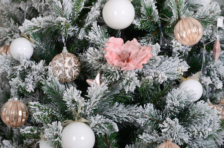 Decorating Christmas tree close up. Decoration bulb, snowy green fir tree, pink x-mas toys and lights. Use for Christmas and New years celebration backgroundの写真素材