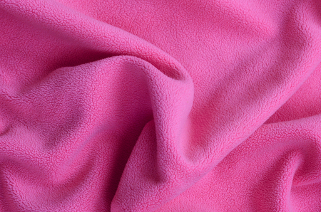 The blanket of furry pink fleece fabric. A background of light pink soft plush fleece material with a lot of relief foldsの写真素材