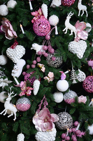 Decorating Christmas tree close up. Decoration bulb, fir tree, pink x-mas toys and lights. Use for Christmas and New years celebration backgroundの写真素材