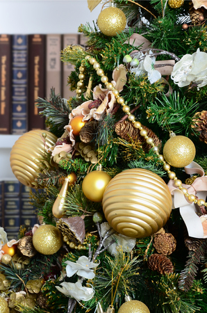 A beautiful decorated Christmas tree on the background of a bookshelf with many books of different colors. Christmas background image of the libraryの写真素材