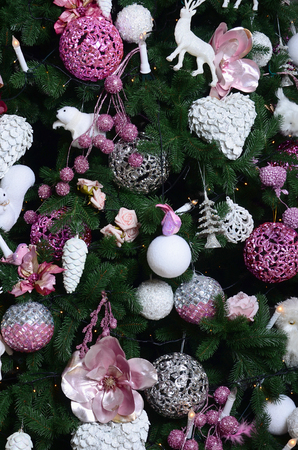 Decorating Christmas tree close up. Decoration bulb, fir tree, pink x-mas toys and lights. Use for Christmas and New years celebration backgroundの写真素材