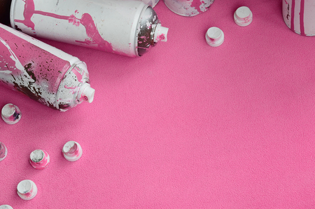 Some used pink aerosol spray cans and nozzles with paint drips lies on a blanket of soft and furry light pink fleece fabric. Classic female design color. Graffiti hooliganism conceptの写真素材