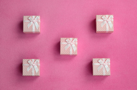 Many small gift boxes in pink color with a small bow lies on a blanket of soft and furry light pink fleece fabric. Packing for a gift to your lovely girlfriendの写真素材