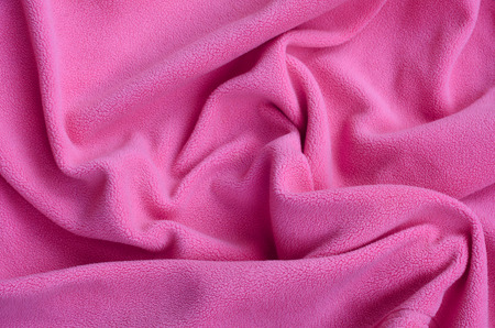 The blanket of furry pink fleece fabric. A background of light pink soft plush fleece material with a lot of relief foldsの写真素材