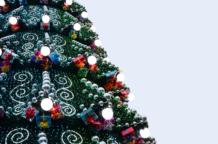 A fragment of a huge Christmas tree with many ornaments, gift boxes and luminous lamps. Photo of a decorated Christmas tree close-up with copy spaceの写真素材