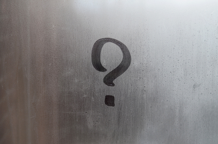 The inscription on glass, question mark concept. Question sign is painted on the surface of misted and wet windowの写真素材