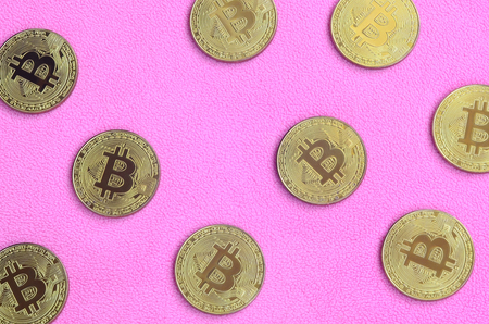 Many golden bitcoins lies on a blanket made of soft and fluffy light pink fleece fabric. Physical visualization of virtual crypto currencyの写真素材