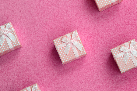 Many small gift boxes in pink color with a small bow lies on a blanket of soft and furry light pink fleece fabric. Packing for a gift to your lovely girlfriendの写真素材