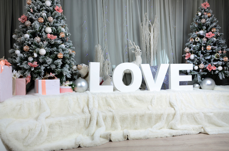 New year cozy interior with a large plush veil, two Christmas trees, toy forest animals and the inscription "love" of big white lettersの写真素材