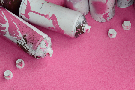 Some used pink aerosol spray cans and nozzles with paint drips lies on a blanket of soft and furry light pink fleece fabric. Classic female design color. Graffiti hooliganism conceptの写真素材