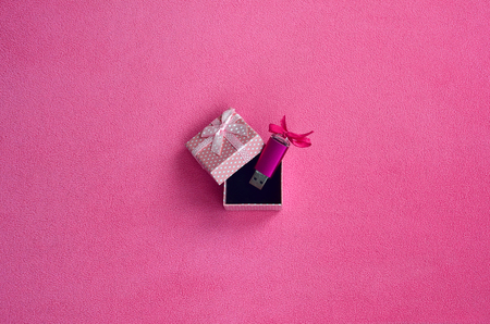 Brilliant pink usb flash memory card with a pink bow lies in a small gift box in pink with a small bow on a blanket of soft and furry light pink fleece fabric. Classic female gift memory card designの写真素材