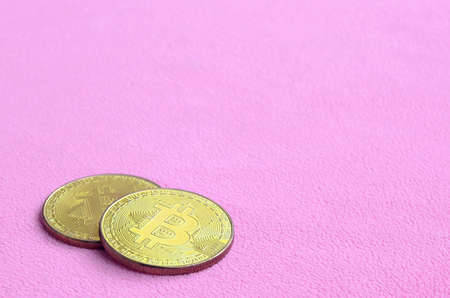 Two golden bitcoins lies on a blanket made of soft and fluffy light pink fleece fabric. Physical visualization of virtual crypto currencyの写真素材