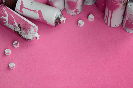 Some used pink aerosol spray cans and nozzles with paint drips lies on a blanket of soft and furry light pink fleece fabric. Classic female design color. Graffiti hooliganism conceptの写真素材