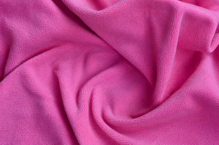 The blanket of furry pink fleece fabric. A background of light pink soft plush fleece material with a lot of relief foldsの写真素材
