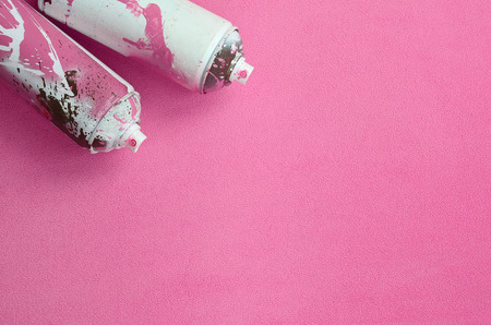 Some used pink aerosol spray cans with paint drips lies on a blanket of soft and furry light pink fleece fabric. Classic female design color. Graffiti hooliganism conceptの写真素材