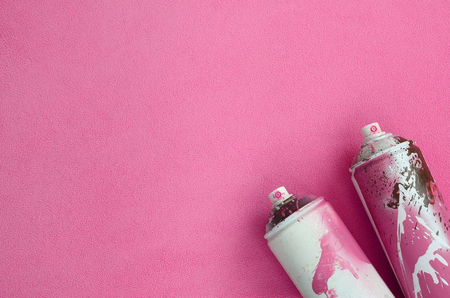 Some used pink aerosol spray cans with paint drips lies on a blanket of soft and furry light pink fleece fabric. Classic female design color. Graffiti hooliganism conceptの写真素材