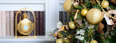A beautiful decorated Christmas tree on the background of a bookshelf with many books of different colors and golden clock. Christmas background image of the libraryの写真素材