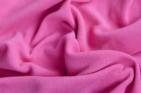 The blanket of furry pink fleece fabric. A background of light pink soft plush fleece material with a lot of relief foldsの写真素材