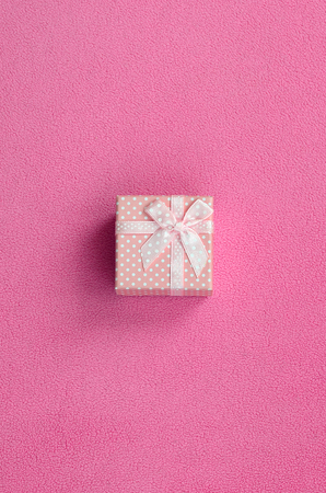 A small gift box in pink with a small bow lies on a blanket of soft and furry light pink fleece fabric. Packing for a gift to your lovely girlfriendの写真素材