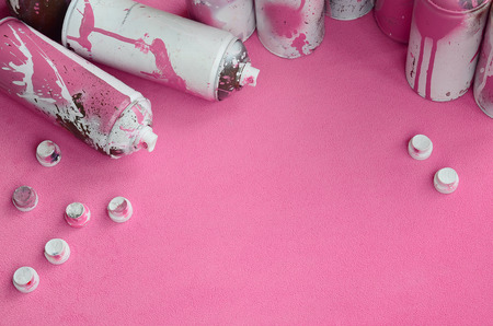 Some used pink aerosol spray cans and nozzles with paint drips lies on a blanket of soft and furry light pink fleece fabric. Classic female design color. Graffiti hooliganism conceptの写真素材