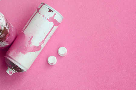 Some used pink aerosol spray cans and nozzles with paint drips lies on a blanket of soft and furry light pink fleece fabric. Classic female design color. Graffiti hooliganism conceptの写真素材