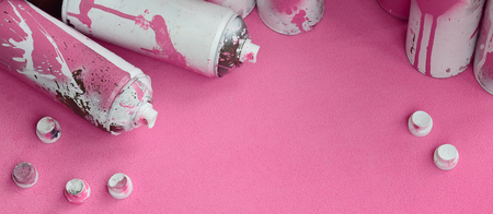 Some used pink aerosol spray cans and nozzles with paint drips lies on a blanket of soft and furry light pink fleece fabric. Classic female design color. Graffiti hooliganism conceptの写真素材
