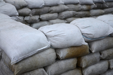 Background of many dirty sand bags for flood defense. Protective sandbag barricade for military use. Handsome tactical bunkerの写真素材
