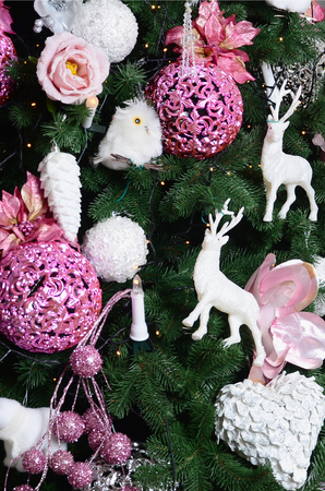 Decorating Christmas tree close up. Decoration bulb, fir tree, pink x-mas toys and lights. Use for Christmas and New years celebration backgroundの写真素材