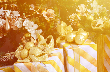 Photo of luxury gift boxes under Christmas tree, New Year home decorations, golden wrapping of Santa presents, festive fir tree decorated with garland, baubles and toys, traditional celebrationの写真素材