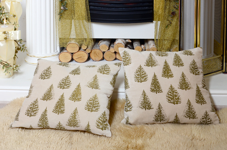 A pair of beige pillows lie on a soft plush veil near the fireplaceの写真素材
