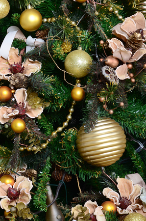 Decorating Christmas tree close up. Decoration bulb, green fir tree, golden x-mas toys and lights. Use for Christmas and New years celebration backgroundの写真素材
