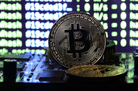 The digital process of cryptocurrency mining by using the GPUs. Bitcoins and video card on a working display and mining screenの写真素材