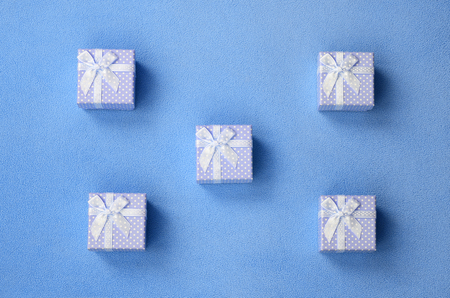 Many small gift boxes in blue color with a small bow lies on a blanket of soft and furry light blue...