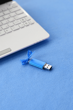 Brilliant blue usb flash memory card with a blue bow lies on a blanket of soft and furry light blue...